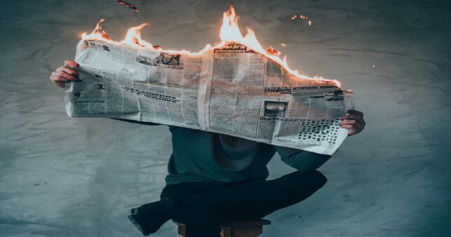 Image of a man sitting comfortably while reading a newspaper on fire ...